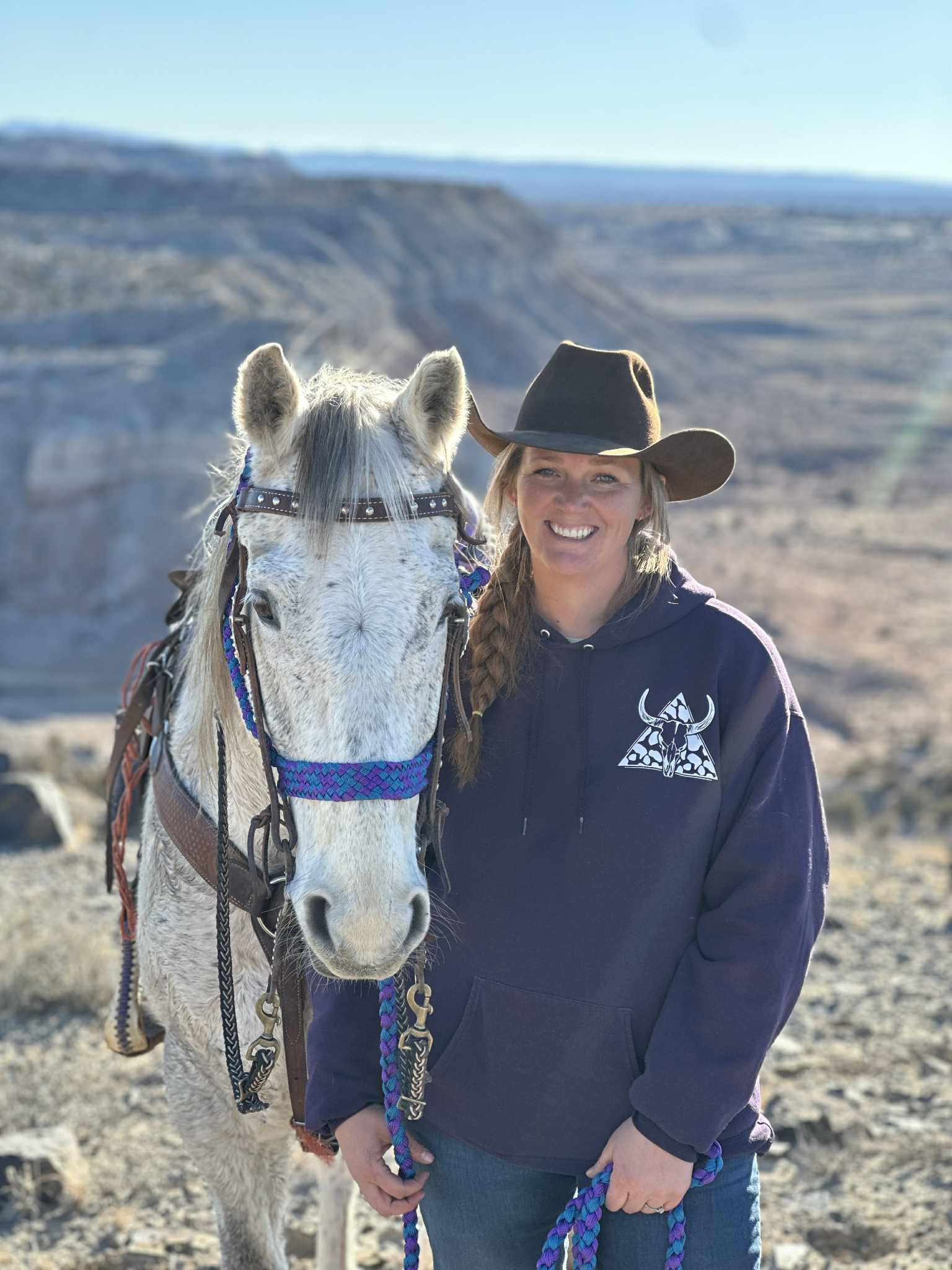 Morgan McDonald, founder of Majesty LC, standing with her horse in the Utah desert canyon landscape